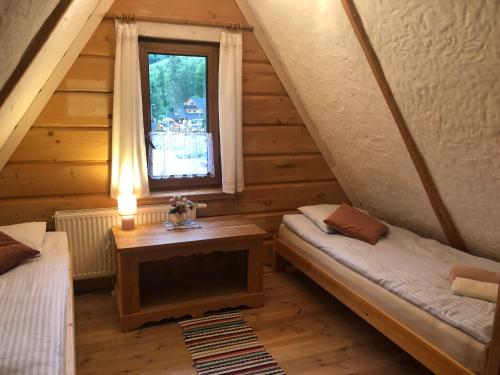 a attic room with two beds and a window at Chata Kozica Kiry in Kościelisko