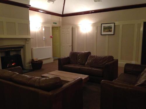 a living room with leather couches and a fireplace at Broadway Country House in Laugharne