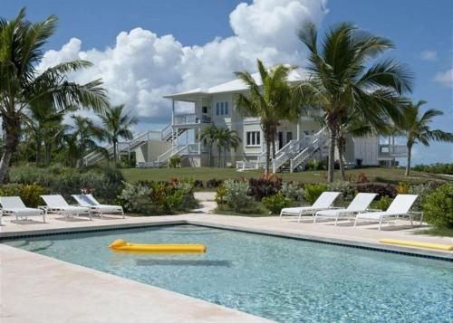 a swimming pool with a yellow raft in front of a house at Buttonwood Reserve by Eleuthera Vacation Rentals in James Cistern