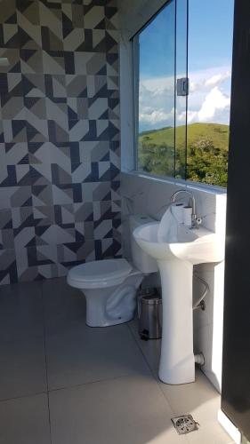 a bathroom with a sink and a toilet and a window at Chácara Sonia & Mineiro in Igaratá