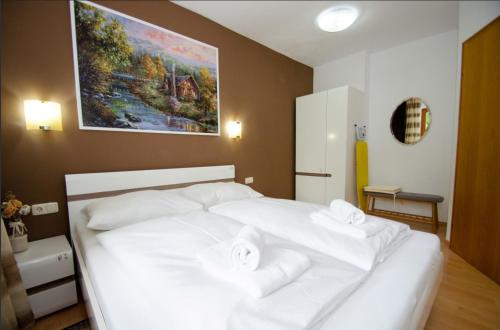 a white bed in a bedroom with a painting on the wall at OTILIA apartment in Zell am See