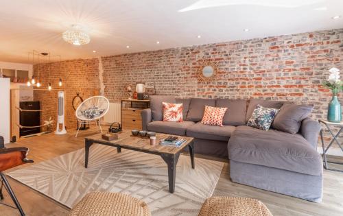 un salon avec un canapé et un mur de briques dans l'établissement Au 21 rue Victor Hugo, à Trouville-sur-Mer