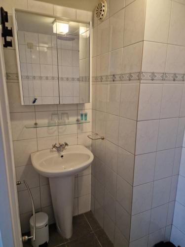 a white bathroom with a sink and a mirror at Beach & Sea view in Zandvoort