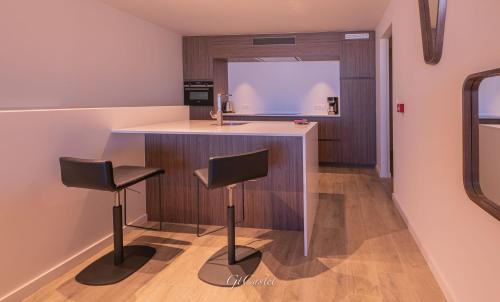 a kitchen with a counter and two stools at Luxueus genieten aan zee: private jacuzzi en sauna in Knokke-Heist