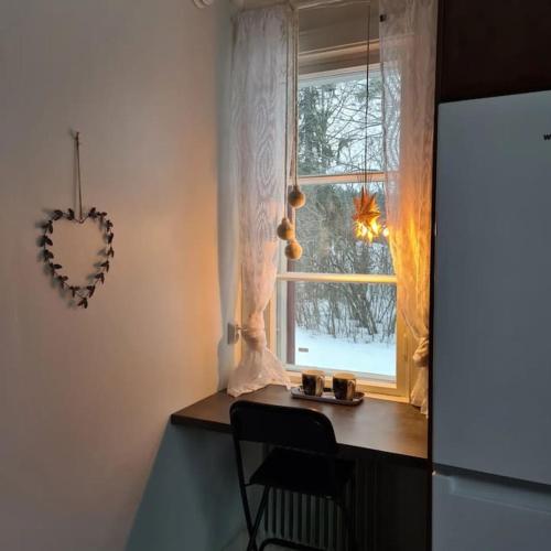 a kitchen with a table and a window with a heart decoration at Ainutlaatuinen huoneisto Vanhassa kyläkoulussa in Purola