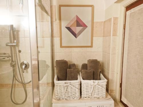 a bathroom with a shower and baskets of towels at Mini suite del borgo antico in Novi Ligure