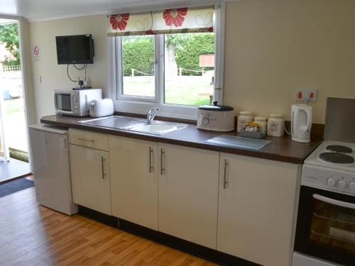 uma cozinha com armários brancos, um lavatório e uma janela em Olive - Uk12694 em Stalham