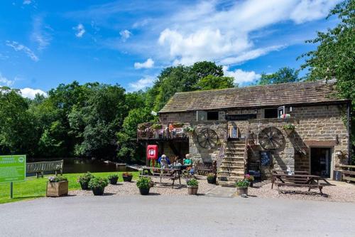 a stone building with people sitting at a table outside at Leylandii 2 Bed Holiday Home in picturesque town. in Knaresborough