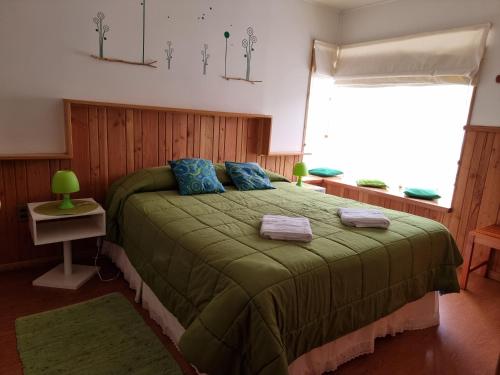 ein Schlafzimmer mit einem grünen Bett und einem Fenster in der Unterkunft La Casa del Árbol Villarrica Cabañas-Piscina-Tinajas in Villarrica