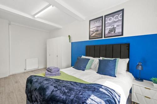 ein Schlafzimmer mit einem großen Bett mit einer blauen Wand in der Unterkunft Sleek 3 bedroom in Sheffield - Sleeps 8 in Wincobank