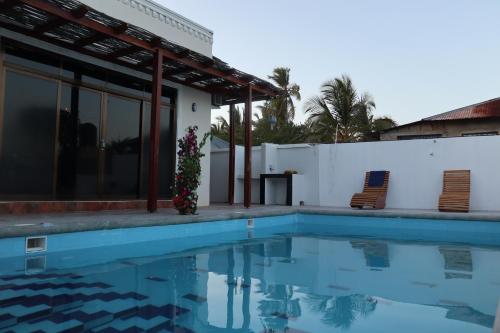 uma casa com piscina e duas cadeiras em Jambo Jambiani Beach Villa, Beautiful private villa at 2 minutes from the Beach em Jambiani