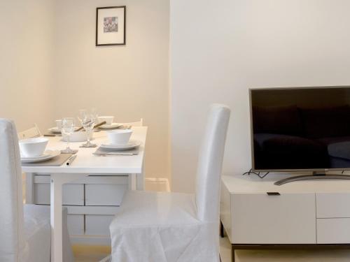a white table with a television and white chairs at Morton Loft in Hathersage