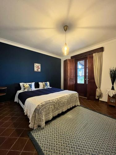 a bedroom with a large bed with a blue wall at Aproveite o sabor do Alentejo in Vila Verde de Ficalho