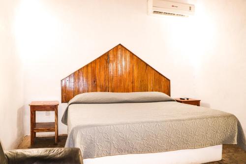 Schlafzimmer mit einem Bett mit einem Kopfteil aus Holz in der Unterkunft San Rafael in Tecomán