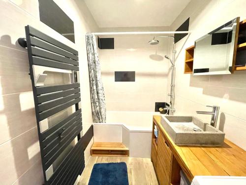 La salle de bains est pourvue d'un lavabo, d'une baignoire et d'une douche. dans l'établissement Le Turgot, proche thermes, à Thonon-les-Bains