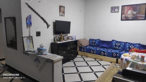 un salon avec un canapé bleu et une télévision dans l'établissement Villa familys, à Fès