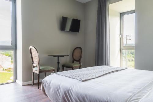 a bedroom with a bed and two chairs and a table at Quinta Dona Iria in Miranda do Corvo
