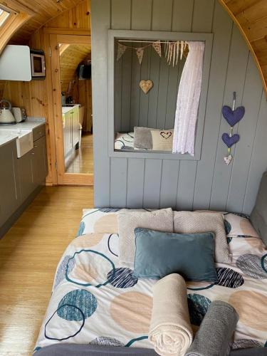 Garden Cottage Glamping Pod في Boncath: سرير في منزل صغير مع مرآة