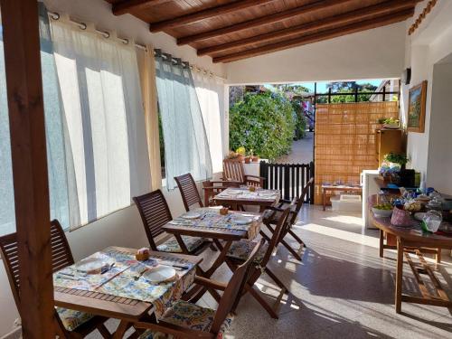 un patio con mesas y sillas de madera y ventanas en B&B Caserta, en Ustica