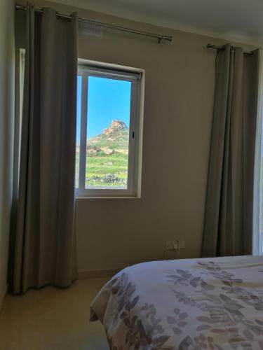 a bedroom with a window with a mountain view at Sea Breeze in Żebbuġ