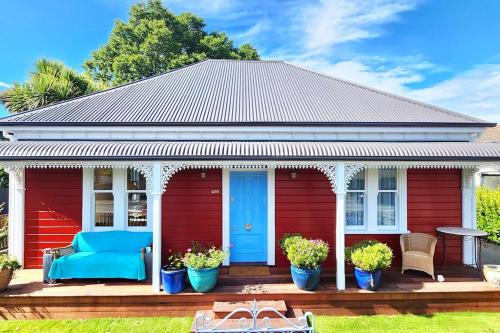a red house with a blue door on a deck at Luxury new 3 bedroom house in central city 5 star in Christchurch