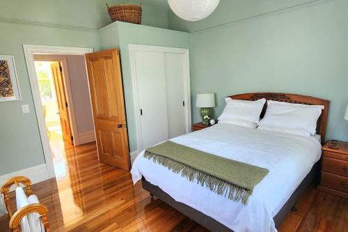 a bedroom with a large white bed and a wooden floor at Luxury new 3 bedroom house in central city 5 star in Christchurch