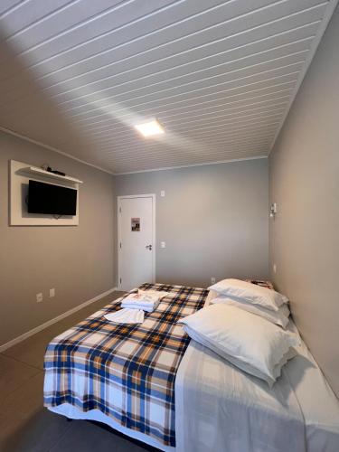 a bedroom with a bed with a plaid blanket at Pousada UpSerra in Urubici