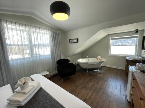 1 dormitorio con cama, bañera y lavamanos en Domaine Belle Plage, en Baie-Saint-Paul