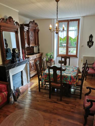 un salon avec une table et une cheminée dans l'établissement Maison de bourg dans le Cantal, à Champagnac