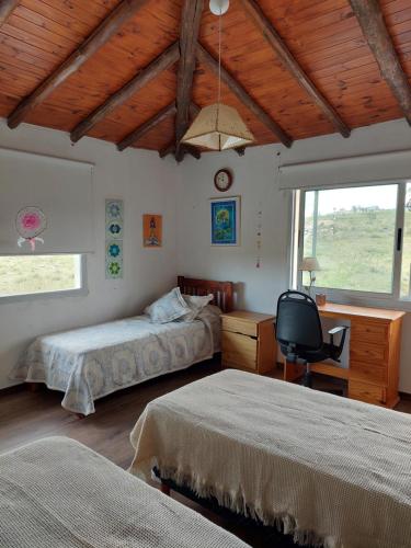 1 dormitorio con 2 camas, escritorio y silla en Sol Mayor en Villa Yacanto