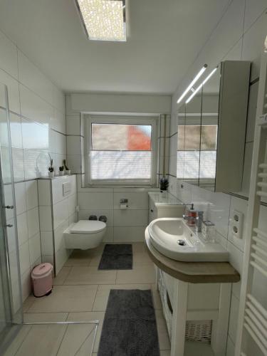 a white bathroom with a sink and a toilet at Süße, komfortable Wohnung - 52qm mit Parkplatz in Rietberg