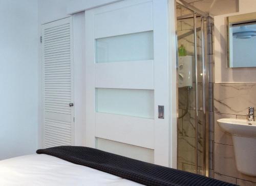 uma casa de banho com um chuveiro e uma cama ao lado de uma porta em Trinity Square, Margate em Kent
