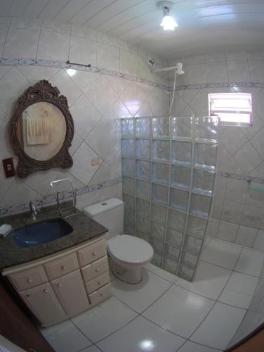 a bathroom with a toilet and a sink and a mirror at Olhar da Barra Hospedagem - Casa Branca in Florianópolis