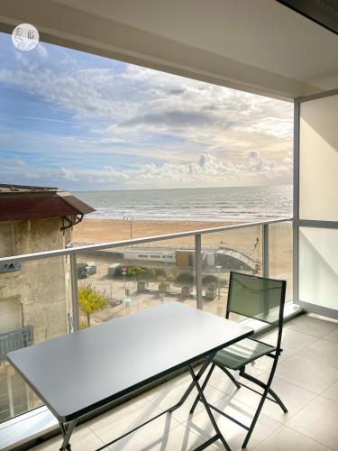 d'une table et d'une chaise sur un balcon avec vue sur la plage. dans l'établissement Au85, Bel appartement, vue océan, pied de la plage, à Saint-Jean-de-Monts