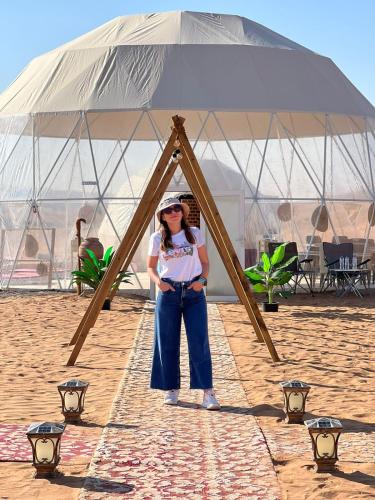 a woman standing in front of a large tent on the beach at Luxury Desert Camp Oman in Al Wāşil