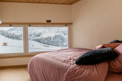 een slaapkamer met een bed en een groot raam bij Duplex cosy au pied des pistes vue montagne in Les Menuires
