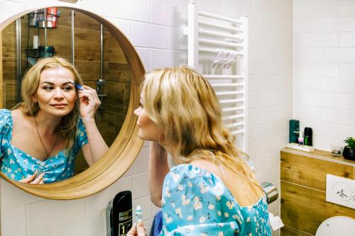 a woman looking at her reflection in a mirror at Bylo Nebylo apartmány in Vítkovice