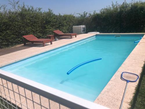a swimming pool with two benches next to it at Alquiler temporal casa Bialet Masse con pileta, cancha de fútbol, mesa de pool y ping pong in Bialet Massé