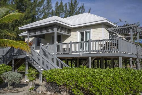 a large white house with a deck and stairs at Sand Dollar Cottage cottage in Rock Sound