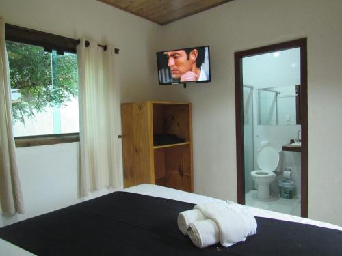a bedroom with a bed with a tv on the wall at Pousada Mandalla in Serra do Cipo