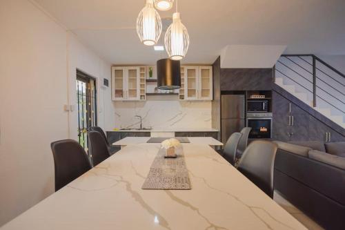 a dining room with a large table and a kitchen at Le Palmiste lovely 2-bedroom duplex with pool in Grand Gaube
