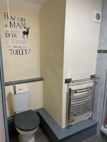 a bathroom with a toilet and a sign that says how can a man be at The Bell Inn in Salisbury