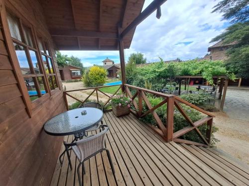 a wooden deck with a table and chairs on it at L'Emiliano Cabañas-Ristorante in Capitán Pastene