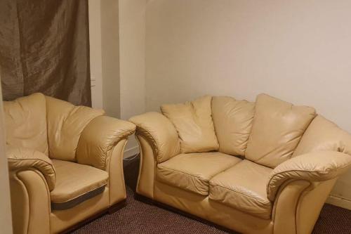 two leather chairs and a couch in a room at Modern flat in Jerviston Court in Motherwell