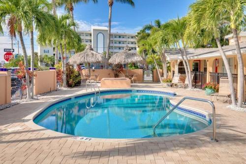 a swimming pool with palm trees in a resort at Steps to the Beach and Restaurants! - Coconut Villa's Suite 1 in St. Pete Beach