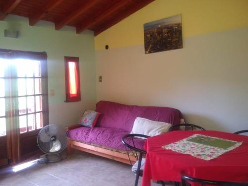 sala de estar con sofá púrpura y mesa en Cabaña en las sierras de Cosquín en Cosquín
