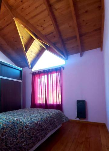 1 dormitorio con 1 cama con cortina roja y ventana en Departamento el encuentro en El Bolsón