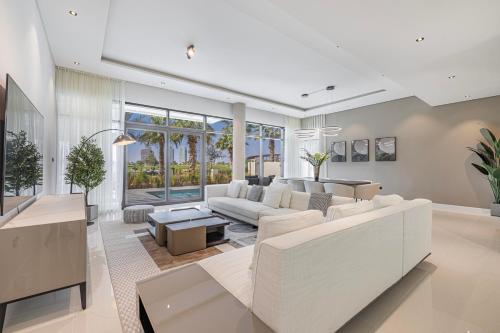 a living room with white furniture and large windows at Daniels Golf Course 5BR Villa with Private Pool in Dubai