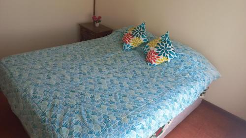 a bed with a blue comforter and two pillows at Departamentos villamar guanaquero in Coquimbo