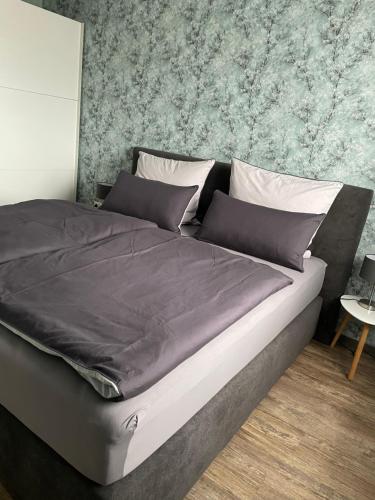 ein großes Bett in einem Schlafzimmer mit einer Wand in der Unterkunft Zum Geigenmüller in Stützengrün